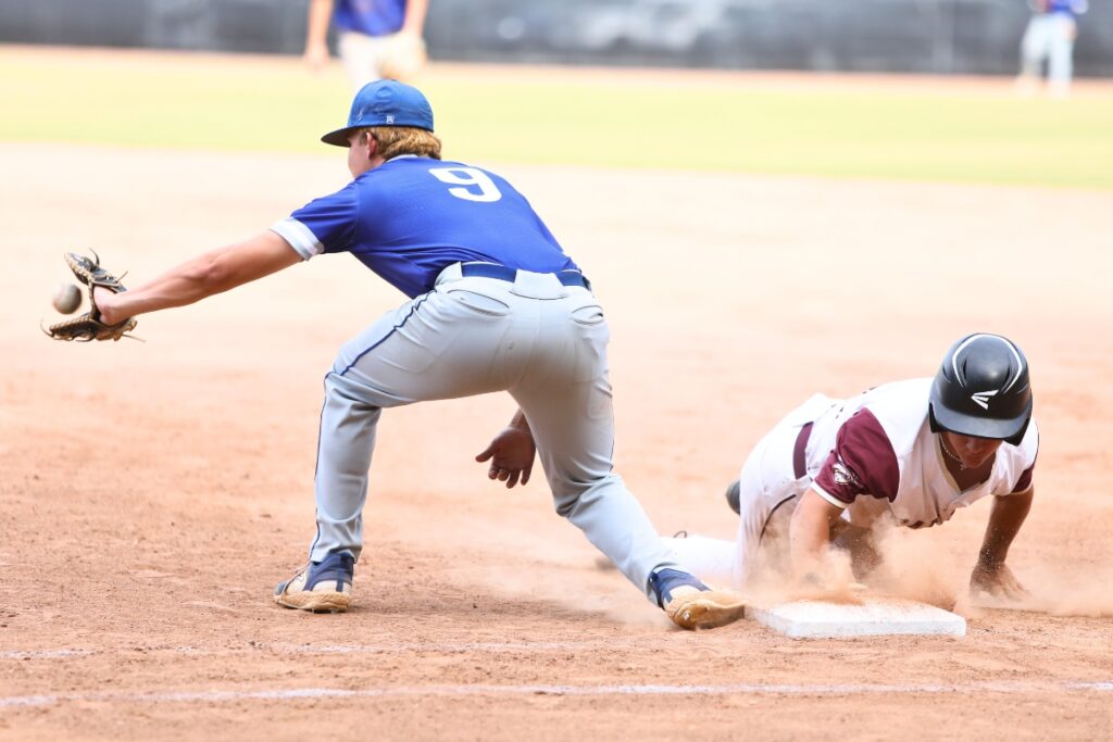 Oak Hall's Brayden Farmer dives safely to first base in the third inning against St. Francis Catholic in game three of the 1A Region 2 Quarterfinals. Photo by C.J. Gish