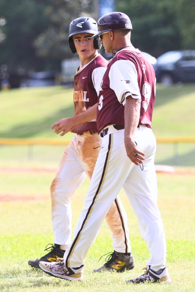 Oak Hall's Brayden Farmer talks with coach Kevin Maris during a third inning timeout against St. Francis Catholic in game two of the 1A Regional quarterfinals. Photo by C.J. Gish