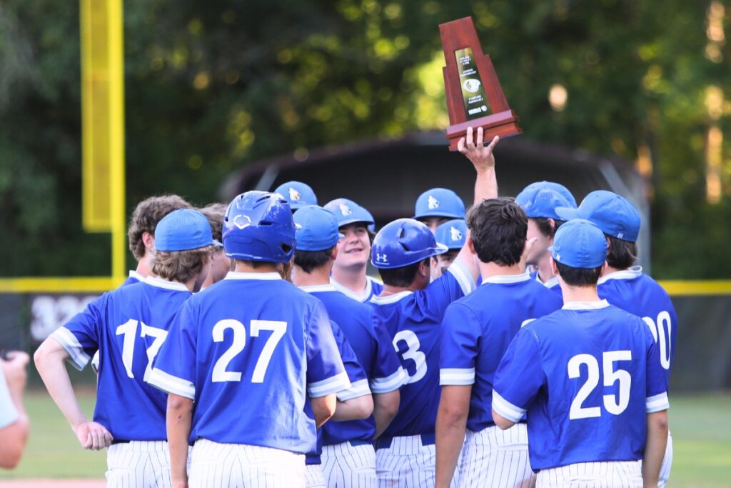 St. Francis Catholic coach Ryan Brown lifts the Class 1A-District 5 trophy up after a 3-2 win over Oak Hall. Photo by C.J. Gish