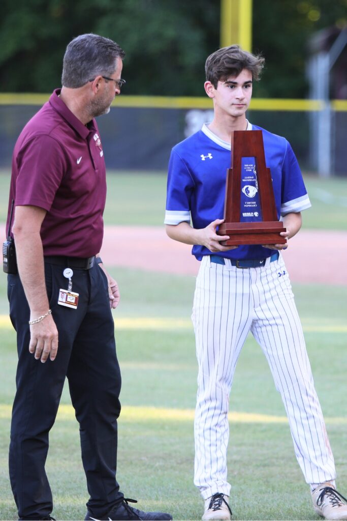 St. Francis Catholic's Cyrus Fariborzian accepts the Class 1A-District 5 championship trophy following a 3-2 win over Oak Hall. Photo by C.J. Gish