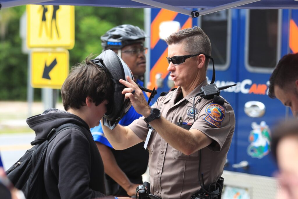 A Florida Highway Patrol trooper secures a helmet to a student at High Springs Community School. 