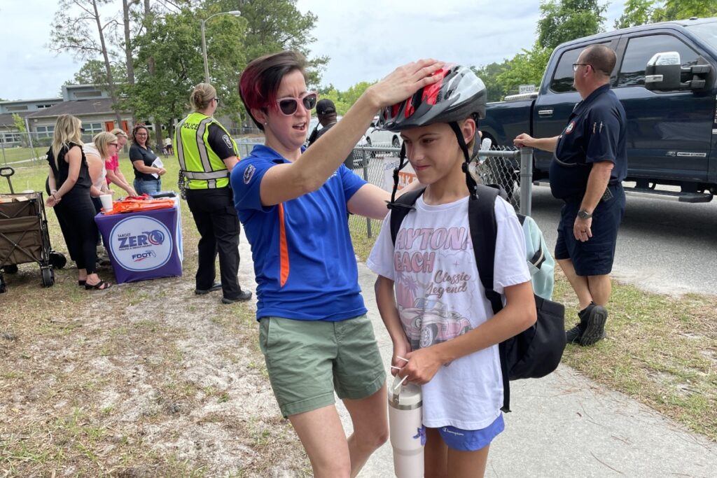 A UF Health employee equips a student with a helmet. 