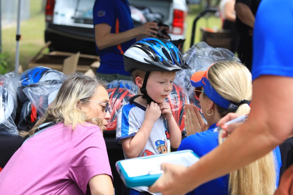 A UF Health employee preps a High Springs student with a new helmet and gives a few simple instructions to property wear it. 