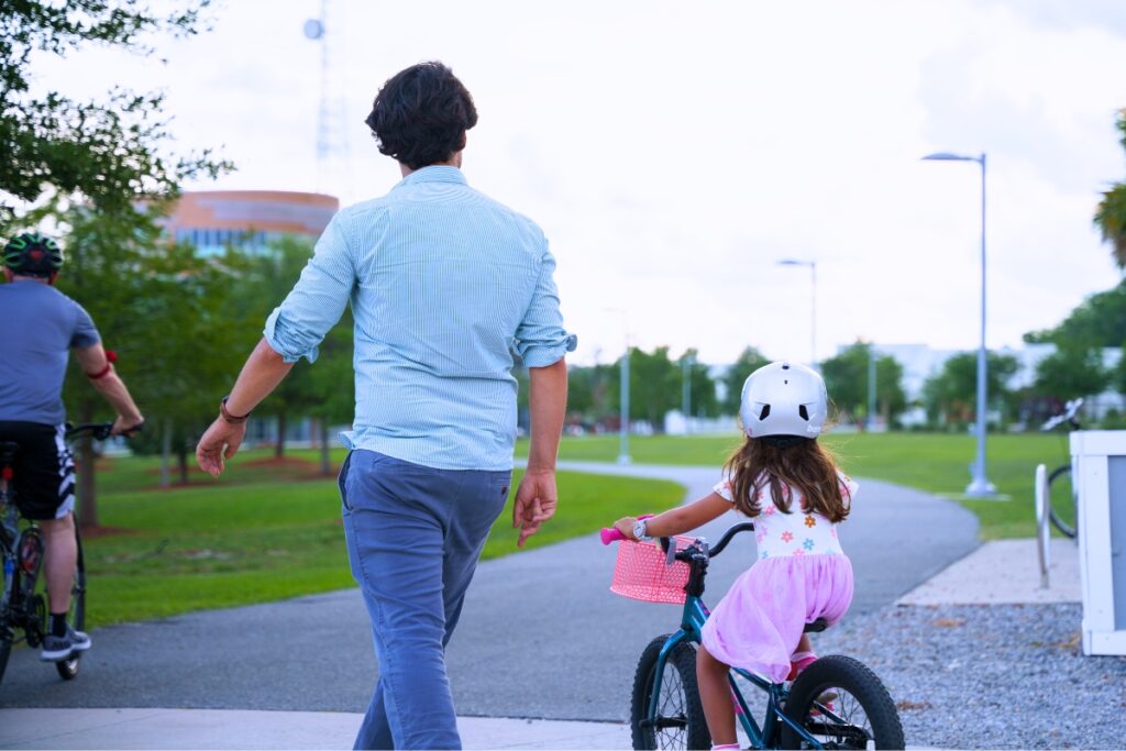 A man walks alongside his daughter during the Ride of Silence on Wednesday at Gainesville's Depot Park. Photo by Tim Rodriquez