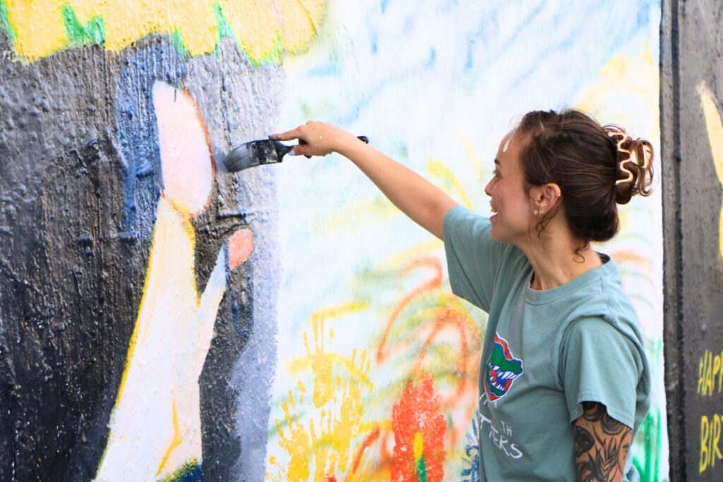 Laura Martin makes brush strokes of paint on the mural. Photo by Lillian Hamman
