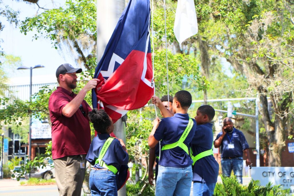 Students from Caring and Sharing Learning School help raise the Juneteenth flag. Photo by Lillian Hamman