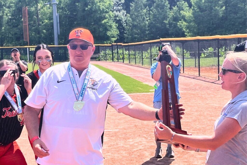 Trenton softball coach Kevin Benson receives the FHSAA Rural state championship trophy after the Tigers defeated Northview (Bratt), 11-1, on Wednesday. Photo by Mike Ridaught