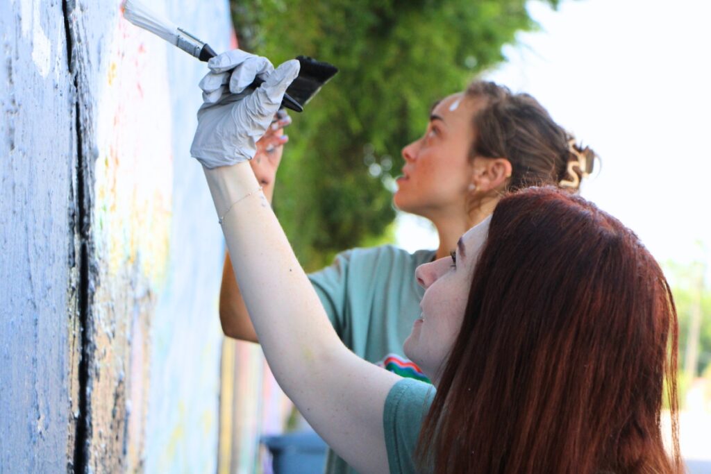 UF Health Psychiatric Hospital employees work on mental health awareness mural on 34th Street wall. Photo by Lillian Hamman