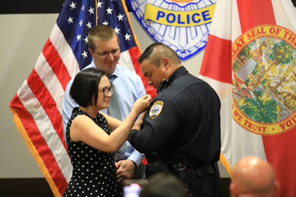 Officer Anthony Lee has his sister pin his badge. 