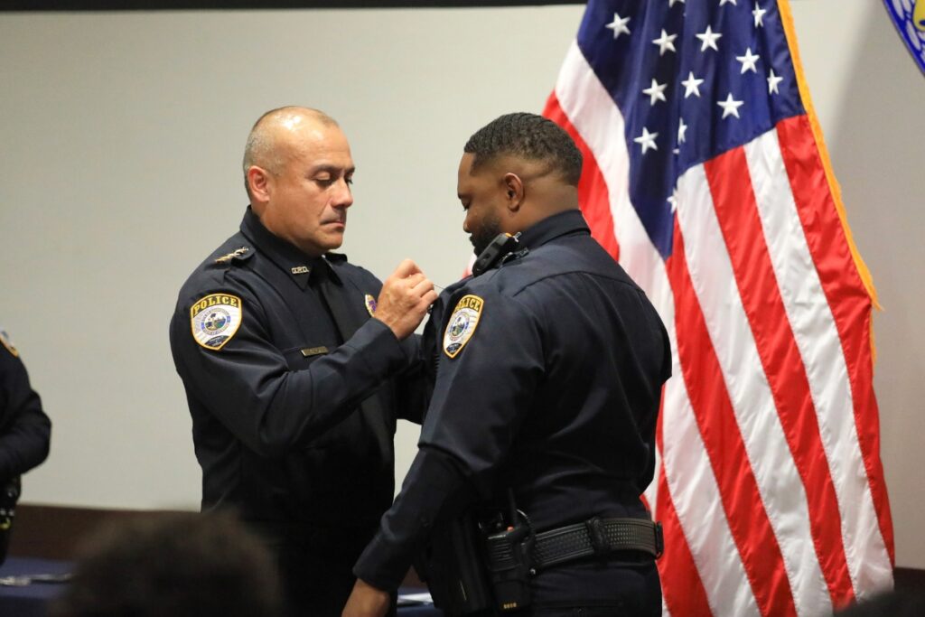 Police Chief Nelson Moya pins a badge on newly-sworn Officer Vontrell Johnson. 
