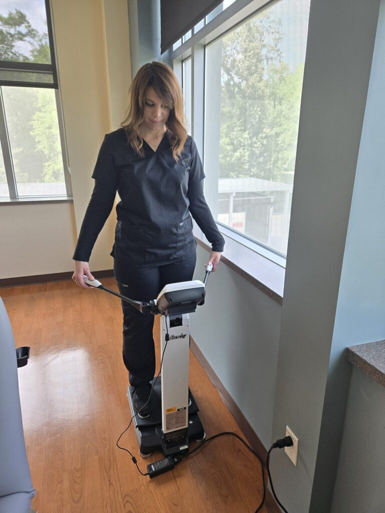A caregiver at UF Health Family Medicine - Springhill demonstrates a bioelectrical impedance device that measures body fat.