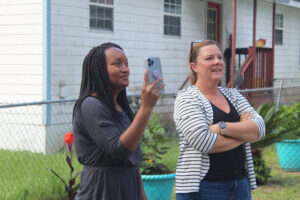 Alachua Habitat for Humanity homeowner Shavonne Washington, left, videos as her home is lifted off the trailer Wednesday morning.