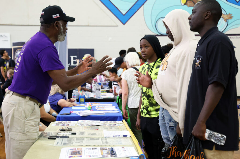 Charlie Ray Jackson (left), president of Manhood Youth Development Foundation Inc., speaks with Jason Roberts (center), Aidan Roberts (right), and Travis Bradley Jr. (far right) about his organization on Saturday.