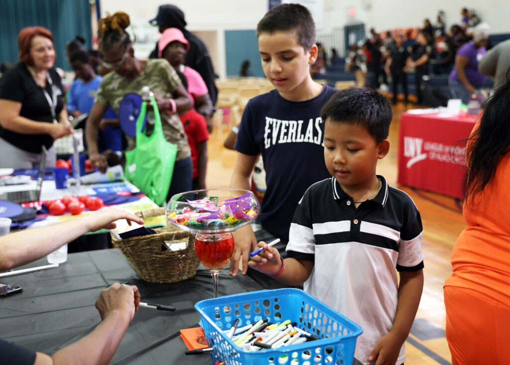 Lam Trinh grabs a pen from a goodie basket at one of many tables for children during the Stop the Violence Back to School Rally at the Martin Luther King Jr. Multipurpose Center on Saturday.