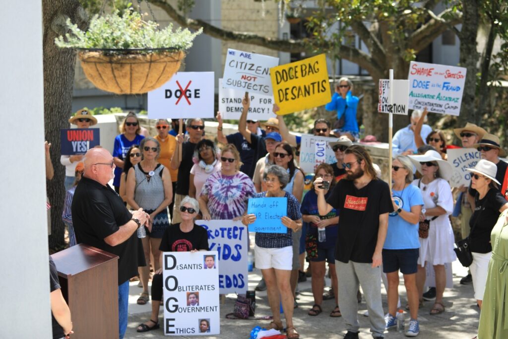 Protestors listened to a series of speakers rail against Gov. Ron DeSantis and his audit into local governments.