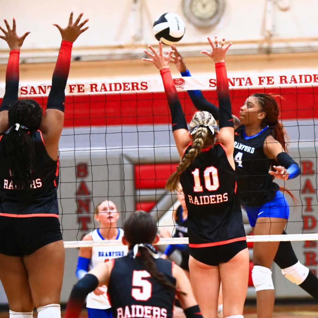 Branford's Adriauna Combs (4) with a hit against Santa Fe's Jordan Matthews (10) and Ajah Graddy (15). Photo by C.J. Gish