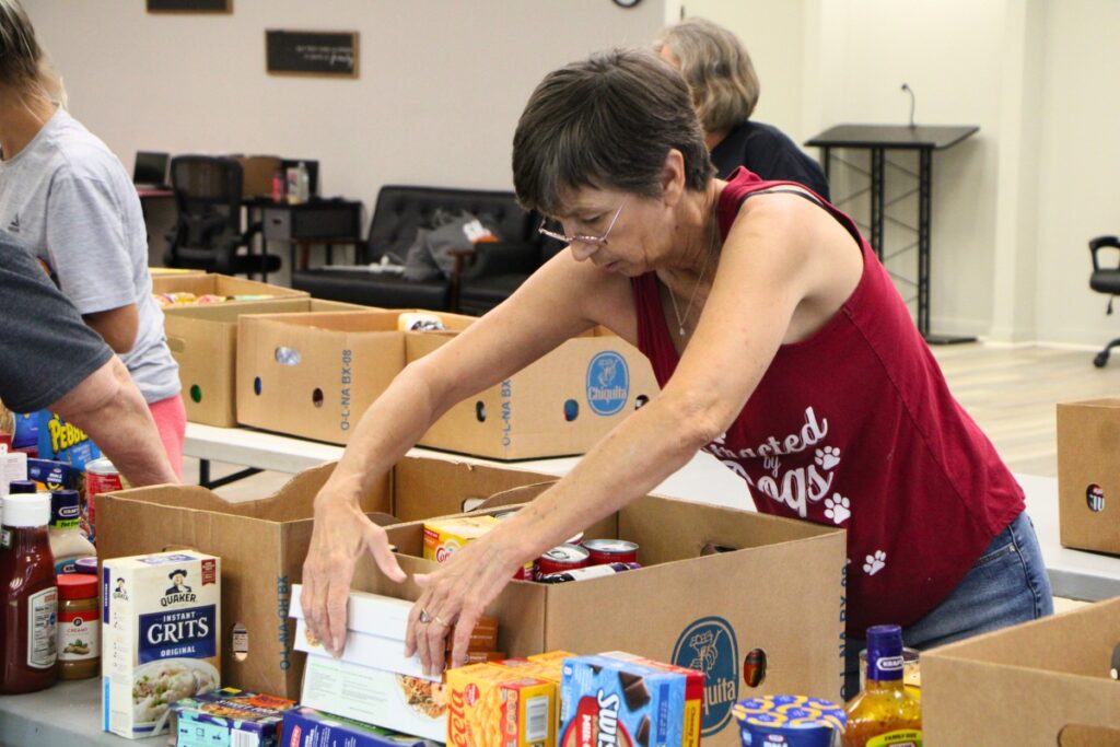 Donna Deal helps restock Deeper Purpose Community Church food pantry. Photo by Lillian Hamman