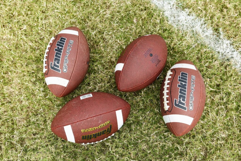 Four footballs. Photo by Mick Haupt-Unsplash