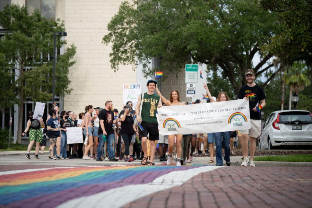 Marchers walk on one of the rainbow crosswalks in downtown Gainesville that the Florida Department of Transportation ordered to be removed. Photo by Tim Rodriquez