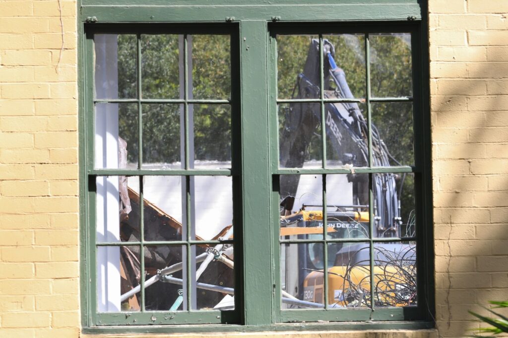 A John Deere backhoe sits in the middle of the half-demolished Thelma Boltin Center. 