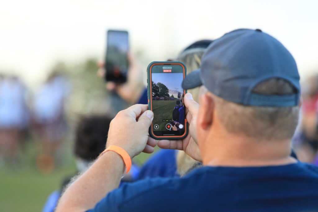 A spectator records the start of the boys varsity cross country meet. Photo by Seth Johnson