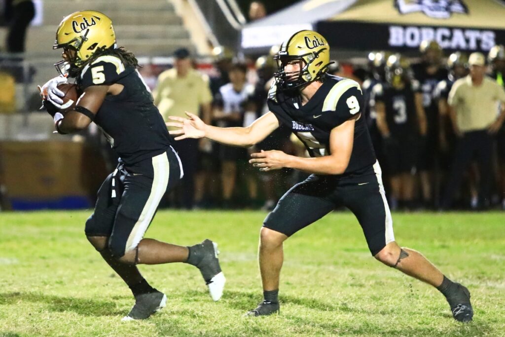 Buchholz quarterback Andrew Whittemore (9) hands the ball off to Caleb Young Jr. (5) against Eastside. Photo by C.J. Gish