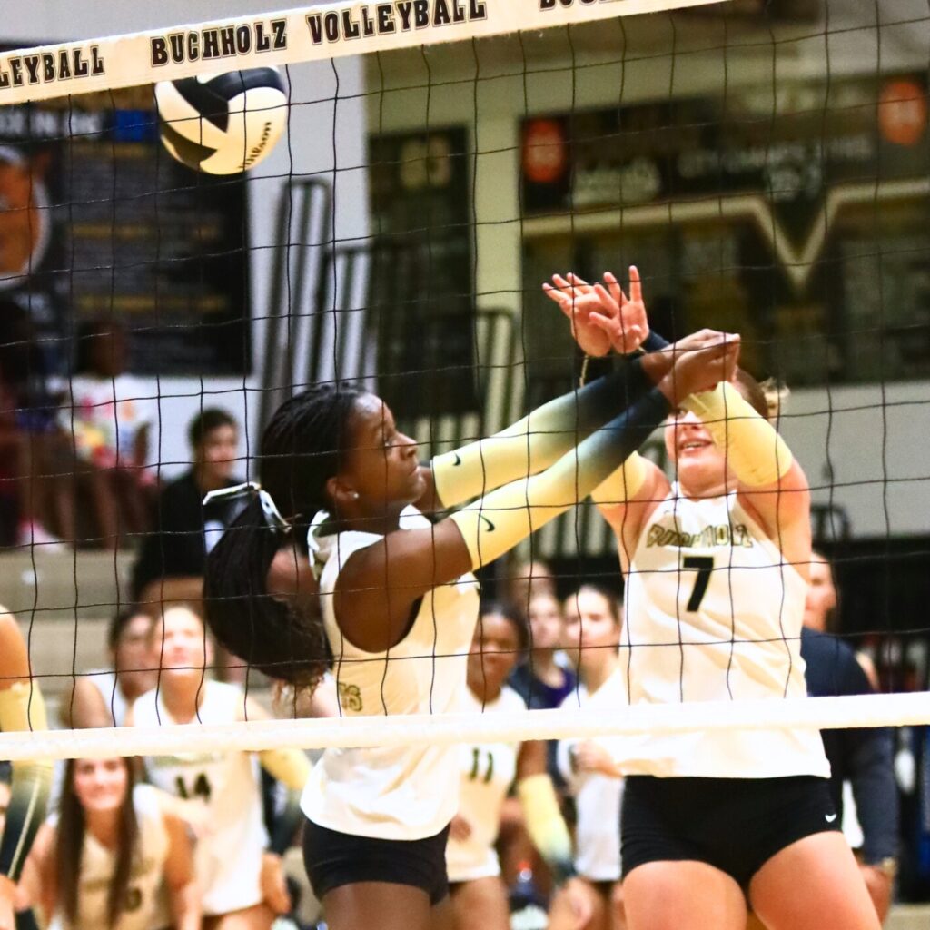 Buchholz's Aaliyah Ray (19) and Julia Almond (7) go for a dig against Gainesville. Photo by C.J. Gish