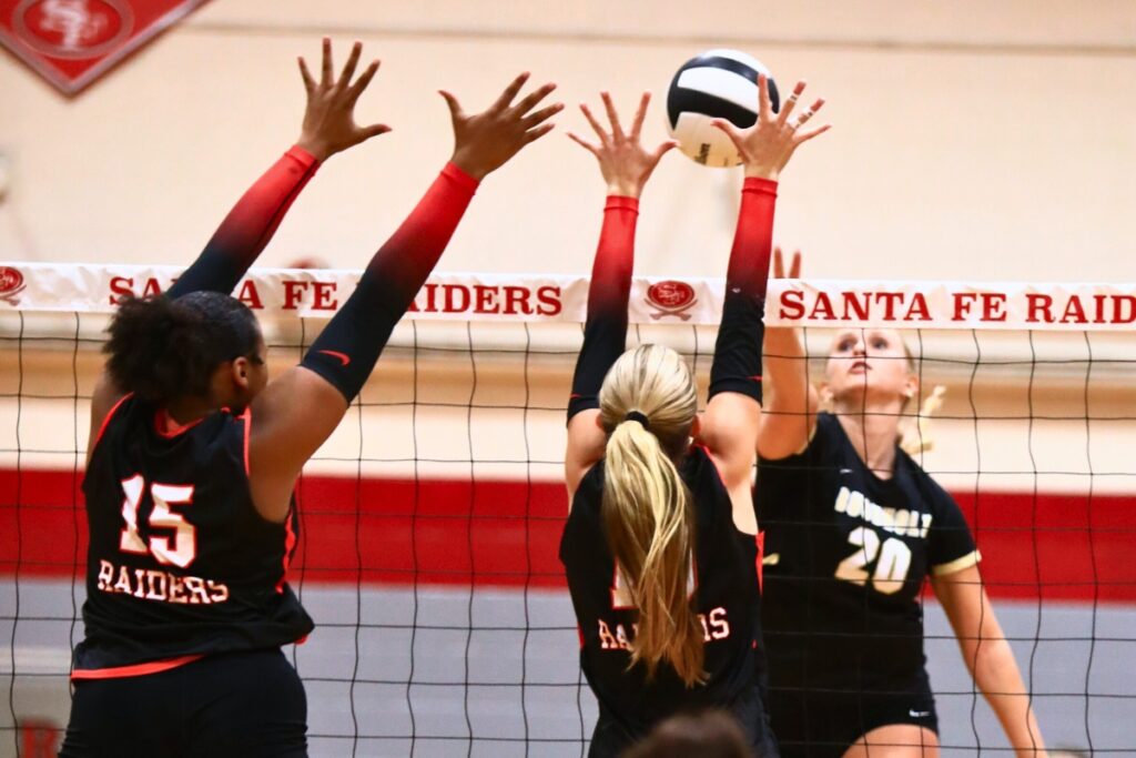 Buchholz's Aubrey Waters (20) goes for a kill against Santa Fe's Ajha Graddy (15) and Jordan Matthews (10). Photo by C.J. Gish