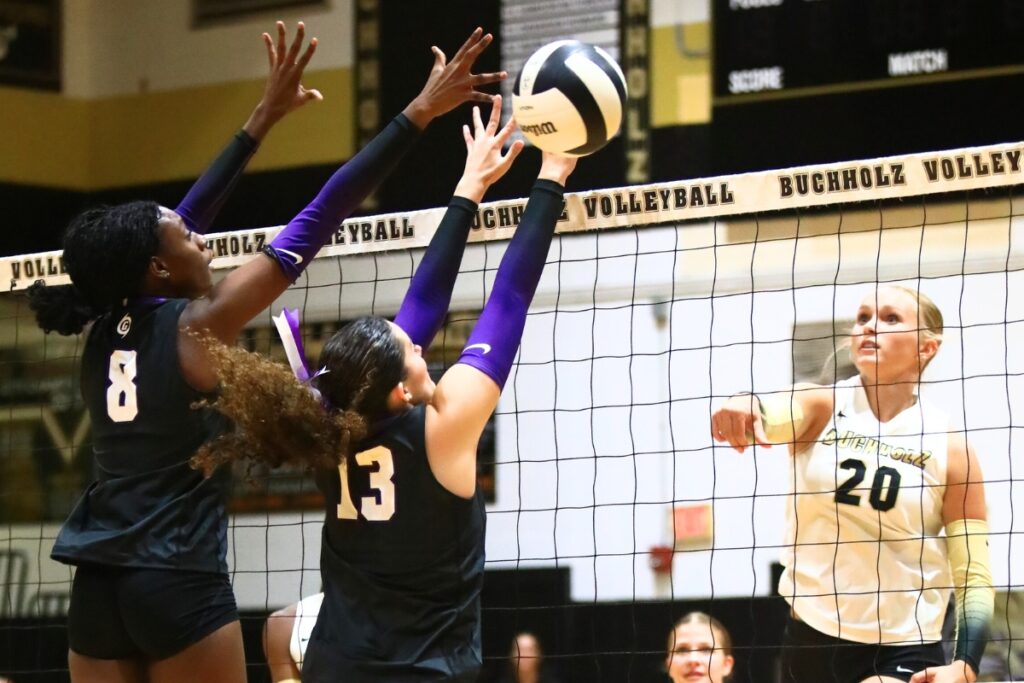 Buchholz's Aubrey Waters (20) with a hit against Gainesville's Jorryn Dye (8) and Sofia Kelly (13). Photo by C.J. Gish