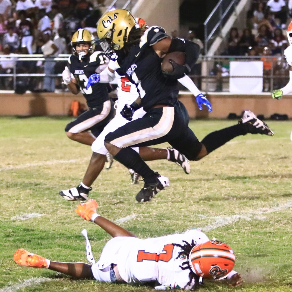 Buchholz's Chris Johnson (1) hurdles Eastside's Jayvon Comer (7). Photo by C.J. Gish 1