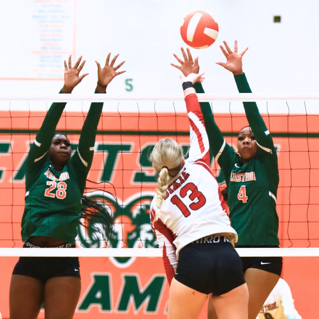 Dixie County's Mia Stalvey (13) with a hit against Eastside's Taylor Flowers (28) and Neeah Mewborn (4). Photo by C.J. Gish