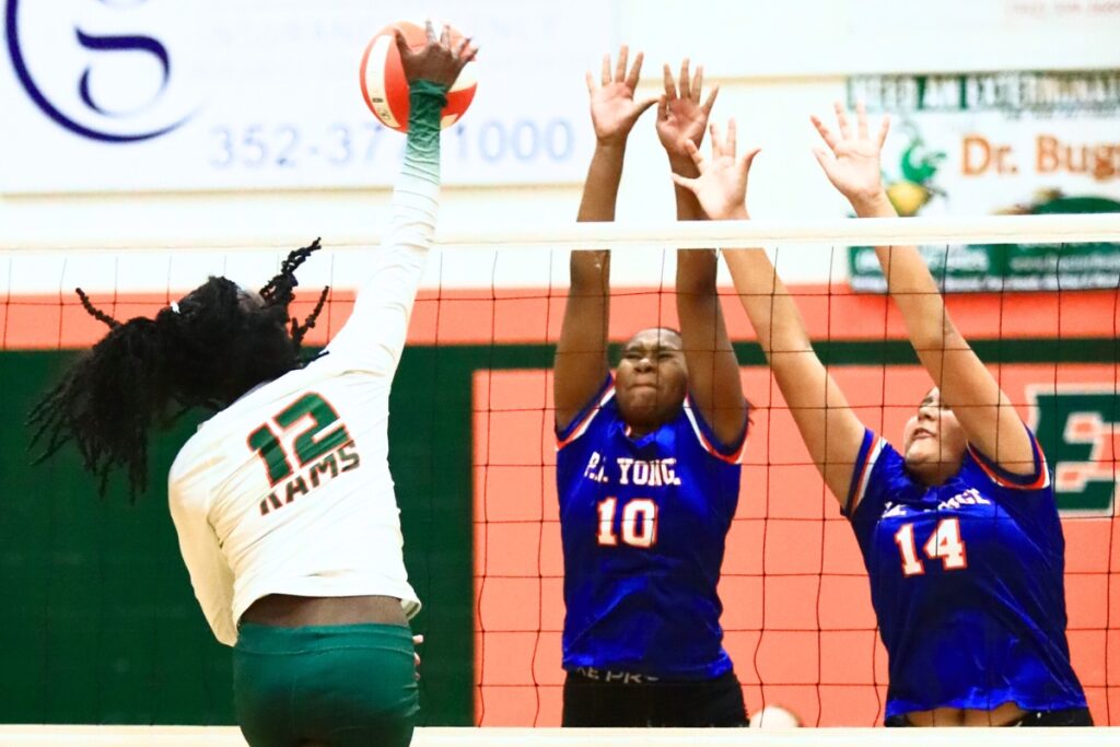 Eastside's Anijah Goss (12) with a hit against P.K. Yonge's Jada Adderly (10) and Ruby Hampton (14). Photo by C.J. Gish