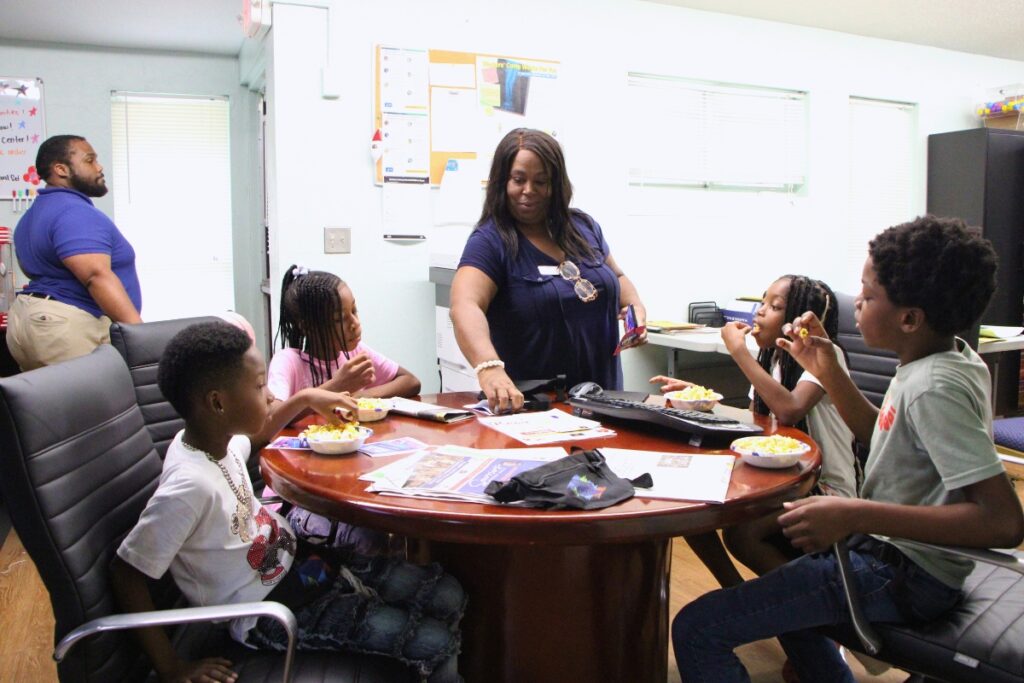 GHA's Freddie Jones (far left) and Ardry Henderson (fourth from left) dishes out popcorn snacks to Junior Newspaper Deliverers. Photo by Lillian Hamman