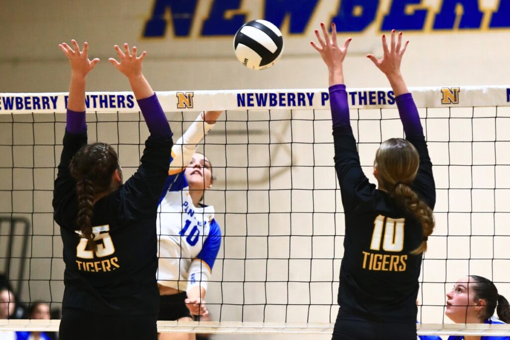 Newberry's Taylor Wells (10) with a hit against Union County's Indi Knox (25) and Mallory Waugh (10). Photo by C.J. Gish