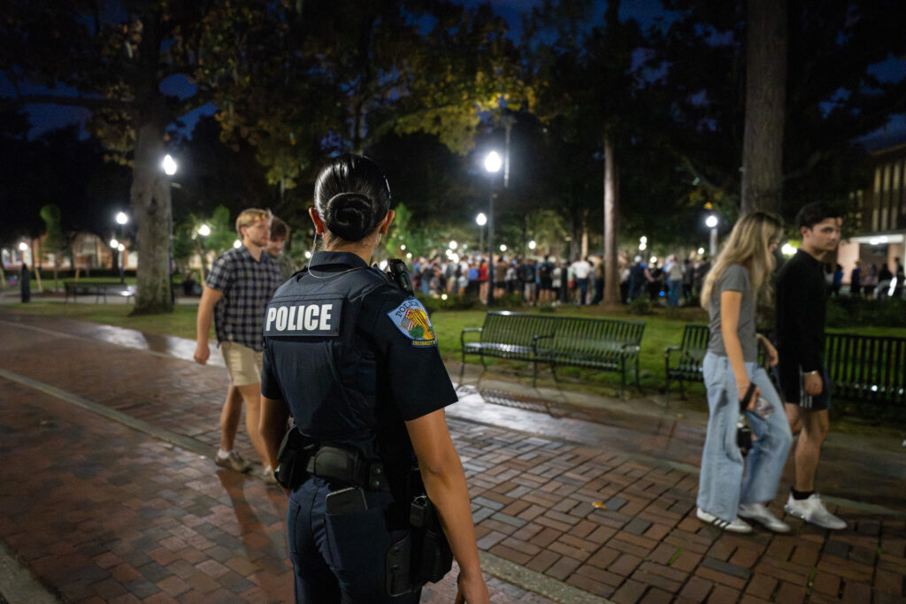 A UF police officer watches students attend the vigil for Charlie Kirk. Several threats against campuses came in the wake of Kirk's death.