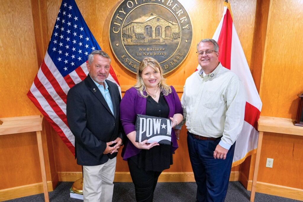 Rep. Kat Cammack presents Newberry Commissioner Mark Clark (far left) and Mayor Tim Marden (far right) new memorial flags. Courtesy of Kat Cammack