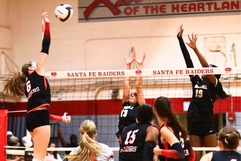 Santa Fe's Delaney Wingenbach (6) with a hit against Buchholz's Delaney Deremer (13) and Aaliyah Ray (19). Photo by C.J. Gish
