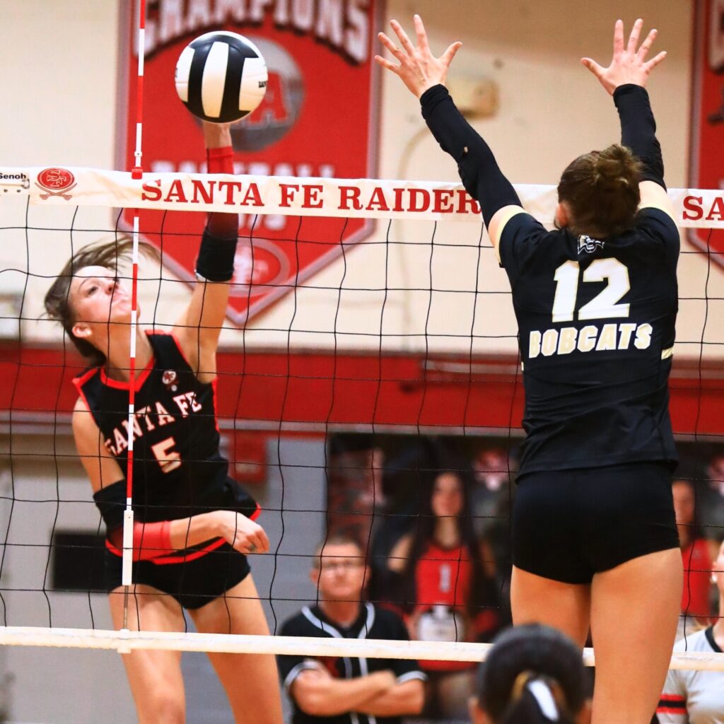 Santa Fe's Ella Schneider (5) with a hit against Buchholz's Taylor Sembower (12). Photo by C.J. Gish