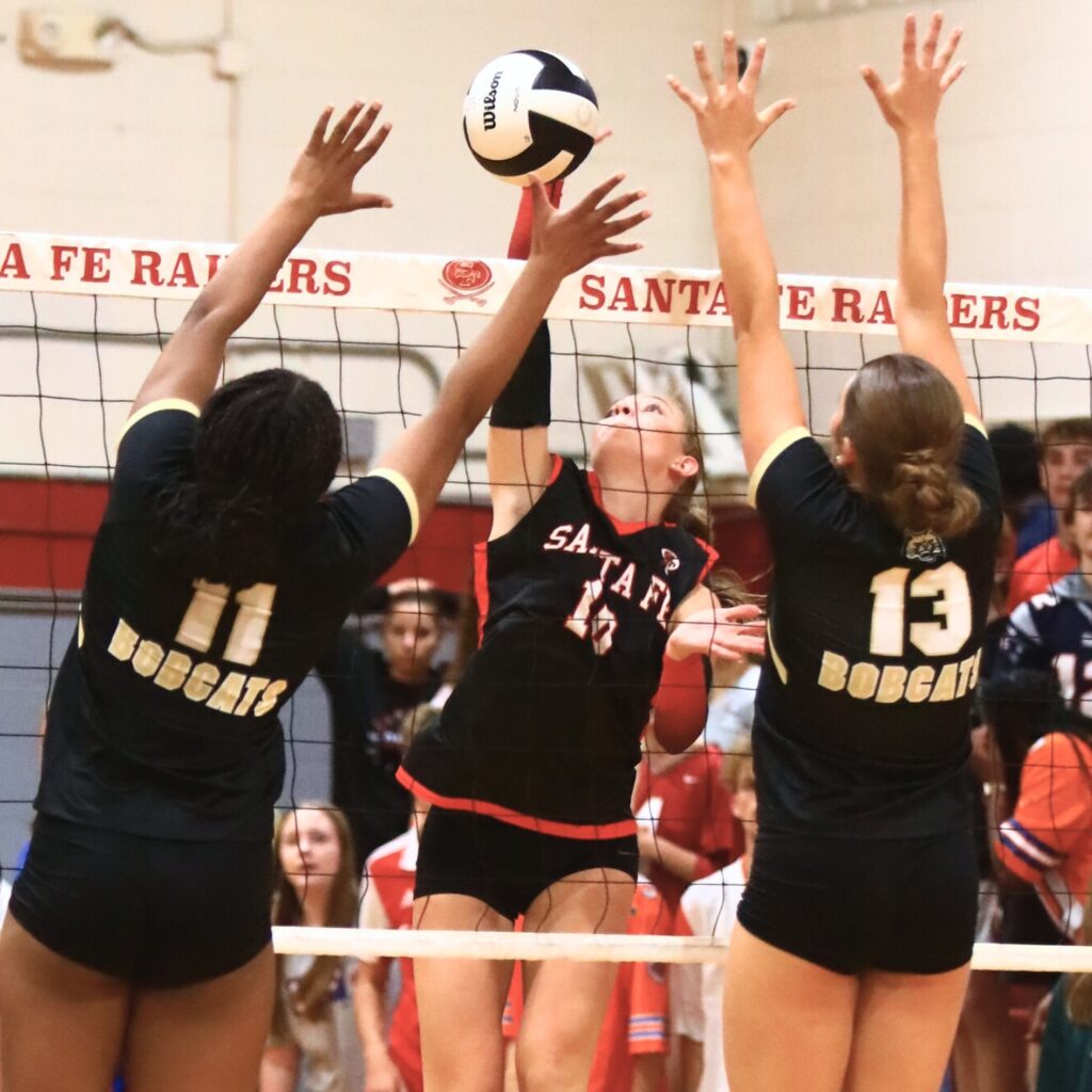 Santa Fe's Jordan Matthews (10) with a hit against Buchholz's Demmi Strappy (11) and Delaney Deremer (13). Photo by C.J. Gish