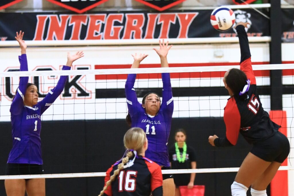 The Rock's Holdyn Moore (15) with a hit against Gainesville's Jacey Carter-Mitchell (1) and Kenzie Carter-Mitchell (11). Photo by C.J. Gish
