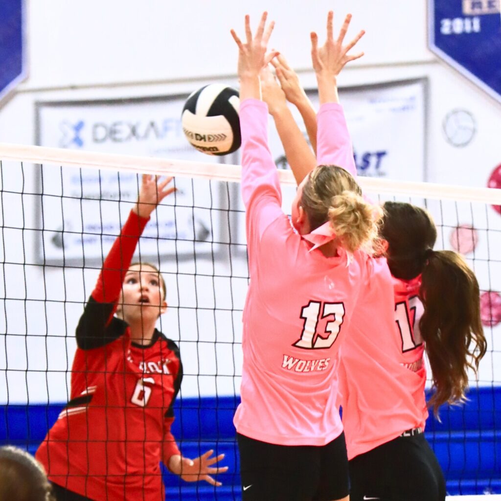 The Rock's Rylan Prodesky (6) with a hit against Saint Francis Catholic's Katelyn Elder (13) and Naomi Magary (12). Photo by C.J. Gish
