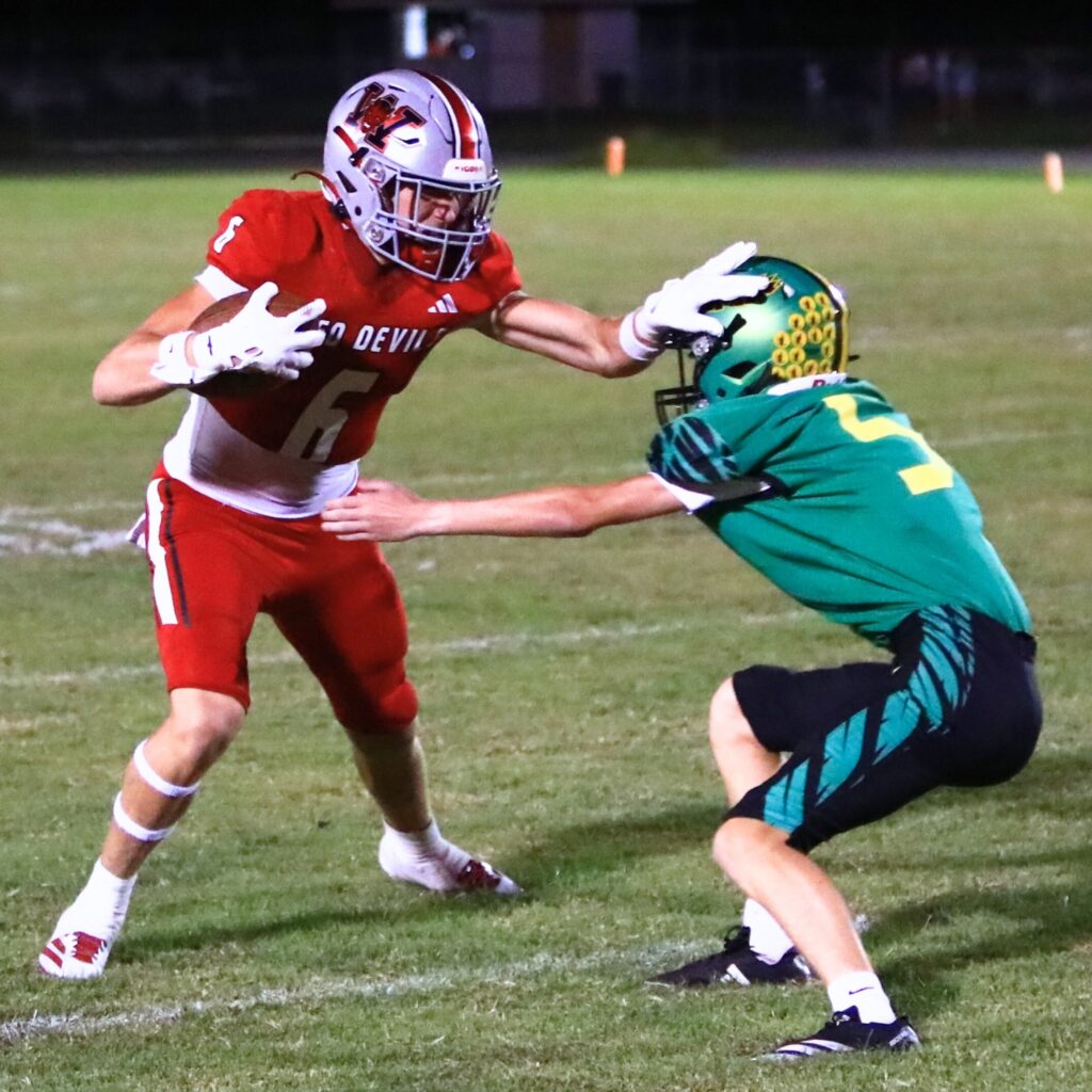 Williston's Sean Bollwage (6) with a second-quarter stiff arm en route to a touchdown against Lake Minneola. Photo by C.J. Gish
