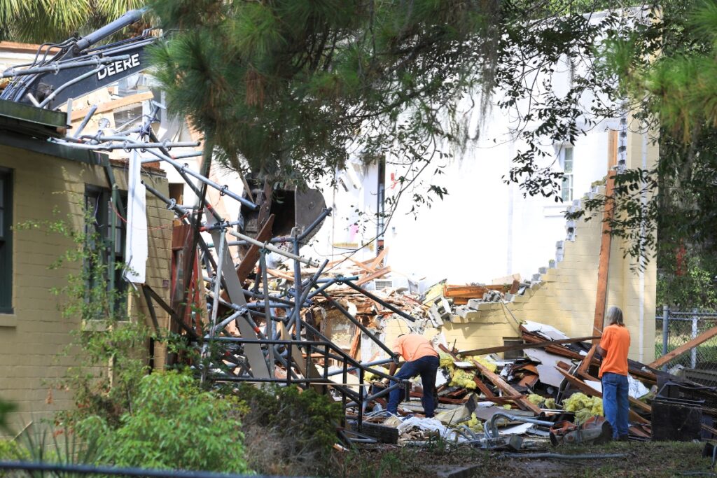Workers remove debris from the Thelma Boltin Center. 