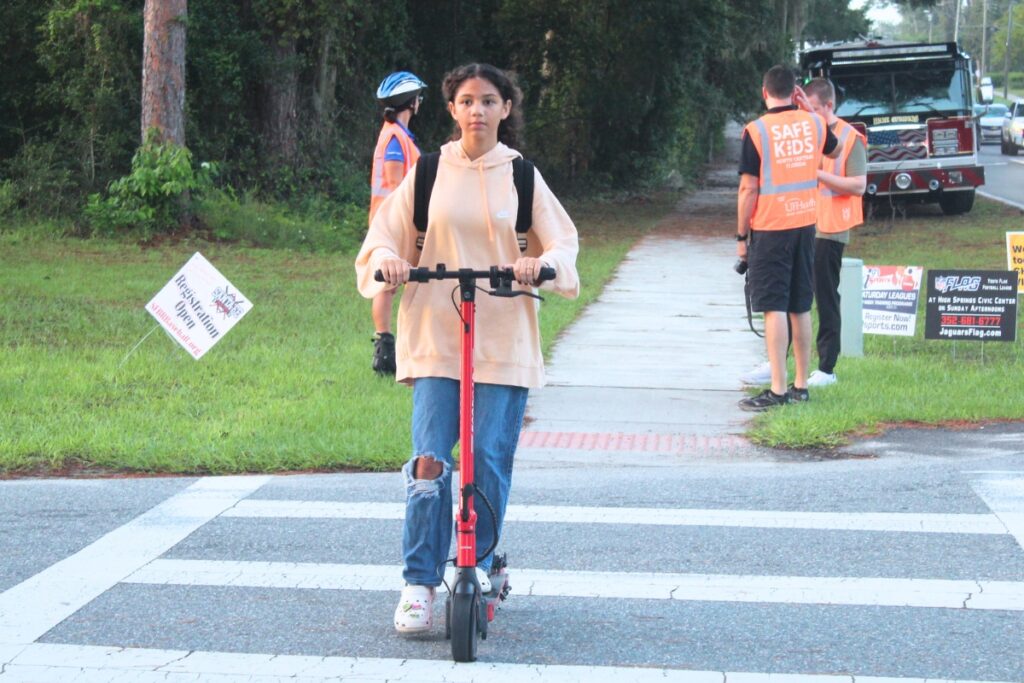 A High Springs Community School student rides her scooter through the crosswalk on Tuesday morning. Photo by Nick Anschultz