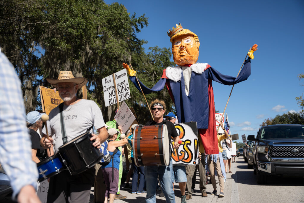 A large prop depicting Trump as a king is hoisted and paraded around the street during the No Kings Gainesville protest 2