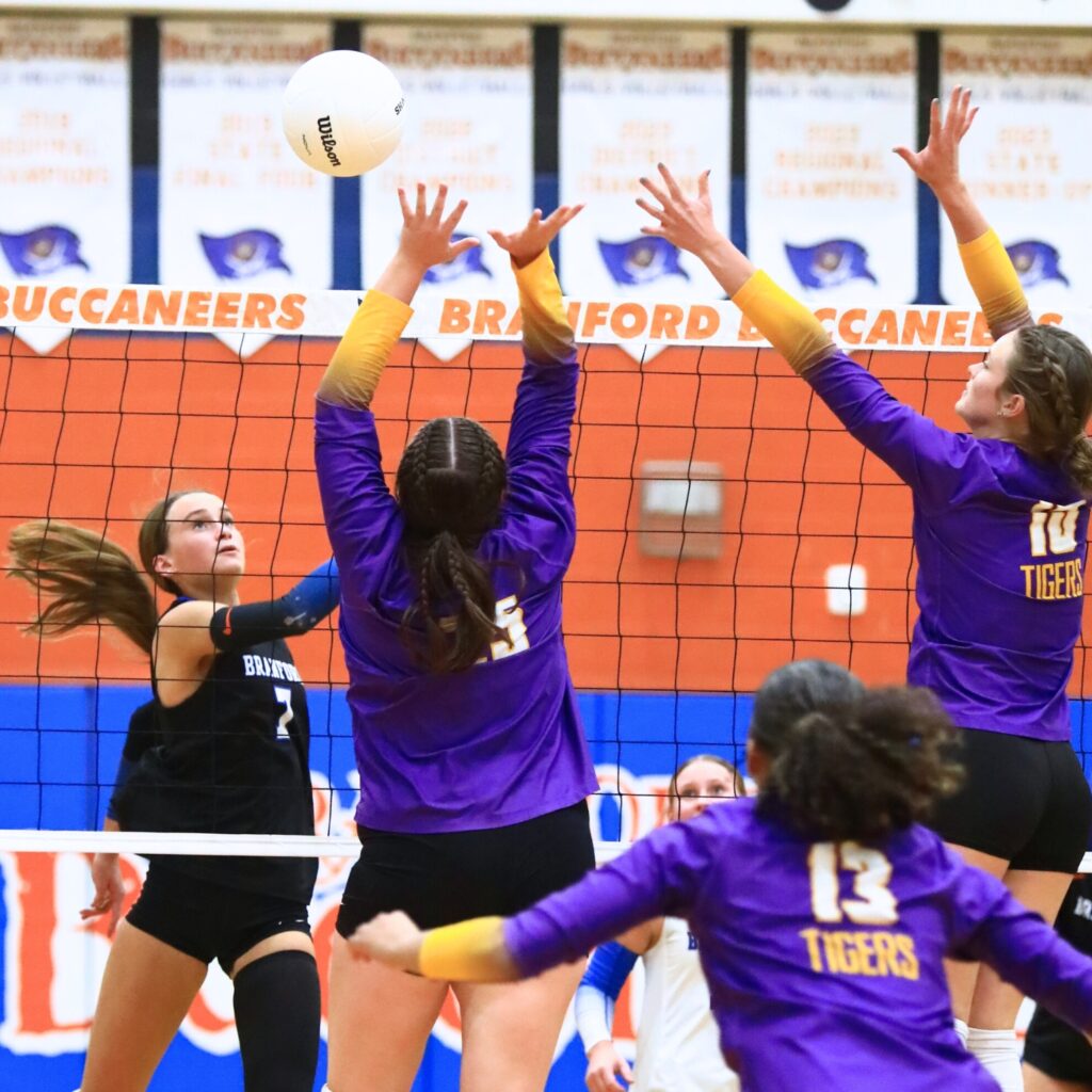 Branford's Lalyn Sikes (7) with a hit against Union County's Indi Knox (25) and Mallory Waugh (10). Photo by C.J. Gish