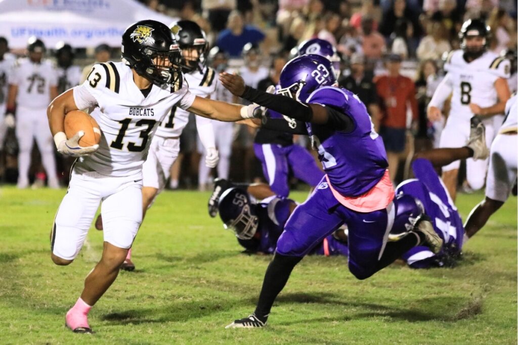 Buchholz's Justin Williams gives a stiff arm as he runs against Gainesville. Photo by Seth Johnson