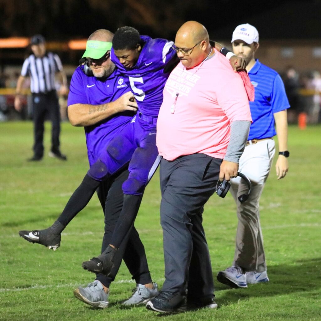 Coaches carry Gainesville quarterback Jaishawn Sanford off the field during the second quarter against Buchholz, but he returned after halftime. Photo by Seth Johnson