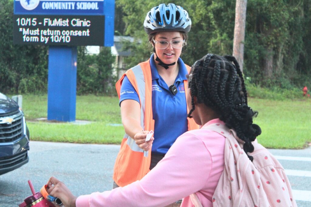 Jordan Zyngier hands a sticker to a student on Tuesday morning. Photo by Nick Anschultz