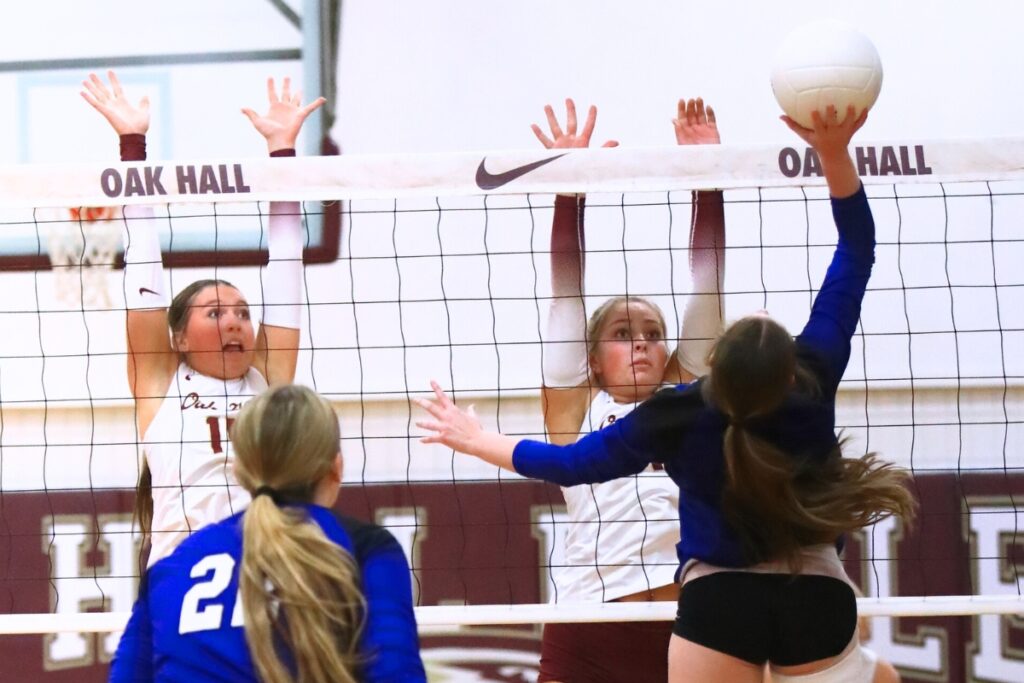 Oak Hall's Kendylle Bishop (14) and Hailey Janes (1) attempt to block a hit by Saint Francis Catholic's Gabrielle Rosado (1). Photo by C.J. Gish